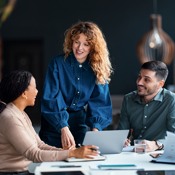 Colleagues in a meeting reviewing documents together at a desk, representing teamwork and collaboration in the workplace.